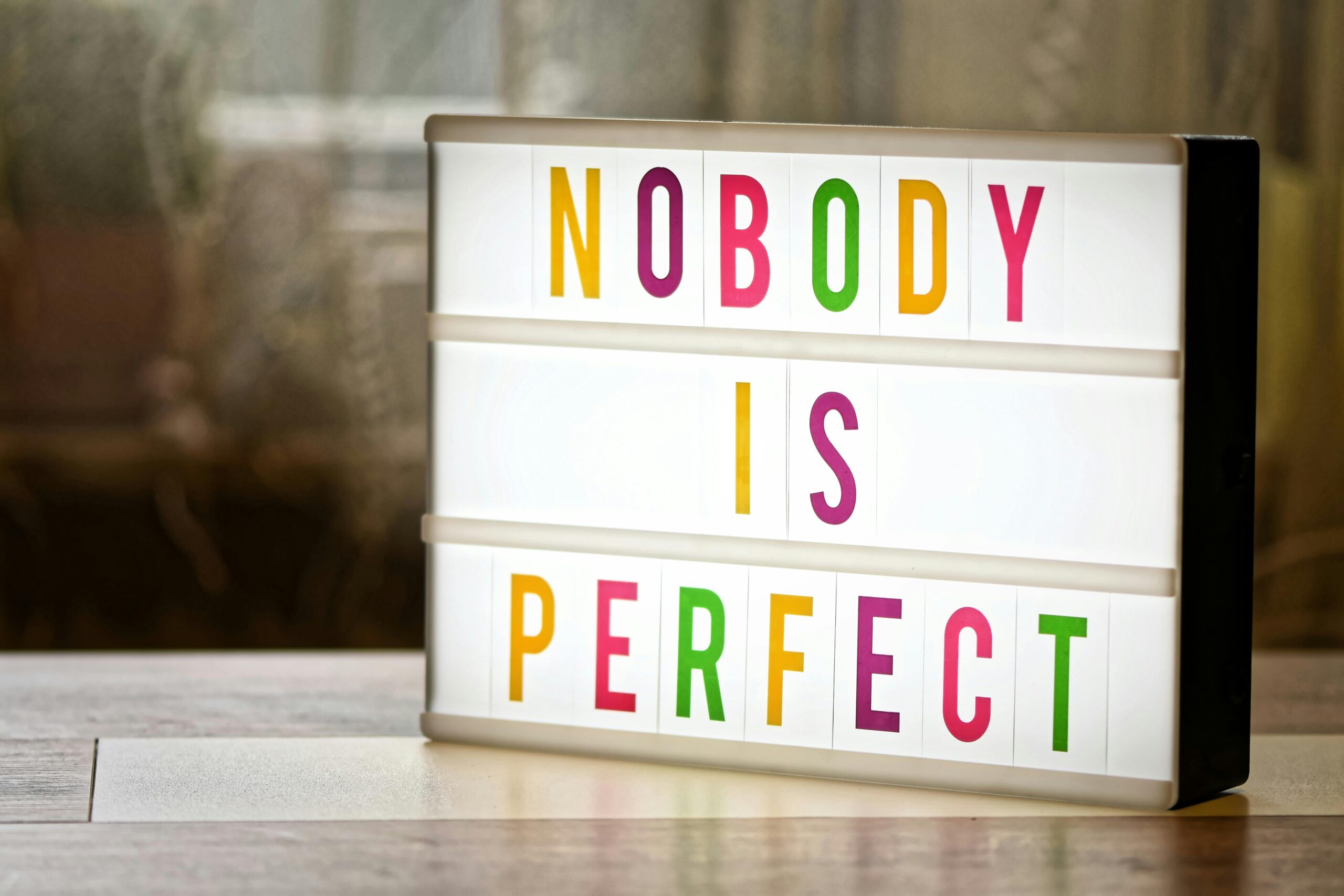 Illuminated lightbox displaying the motivational slogan 'Nobody is Perfect'.